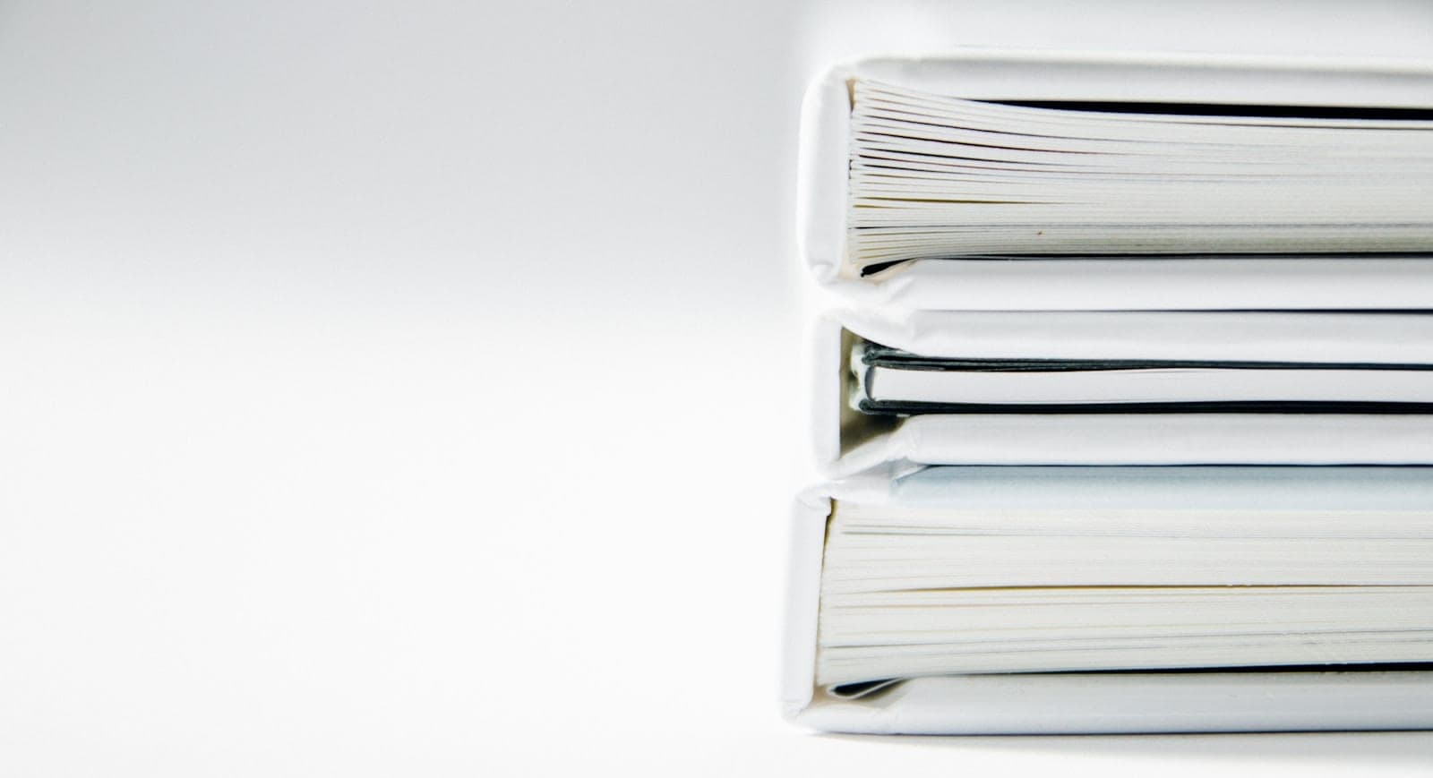 Stos grubych segregatorów z dokumentami na jasnym blacie